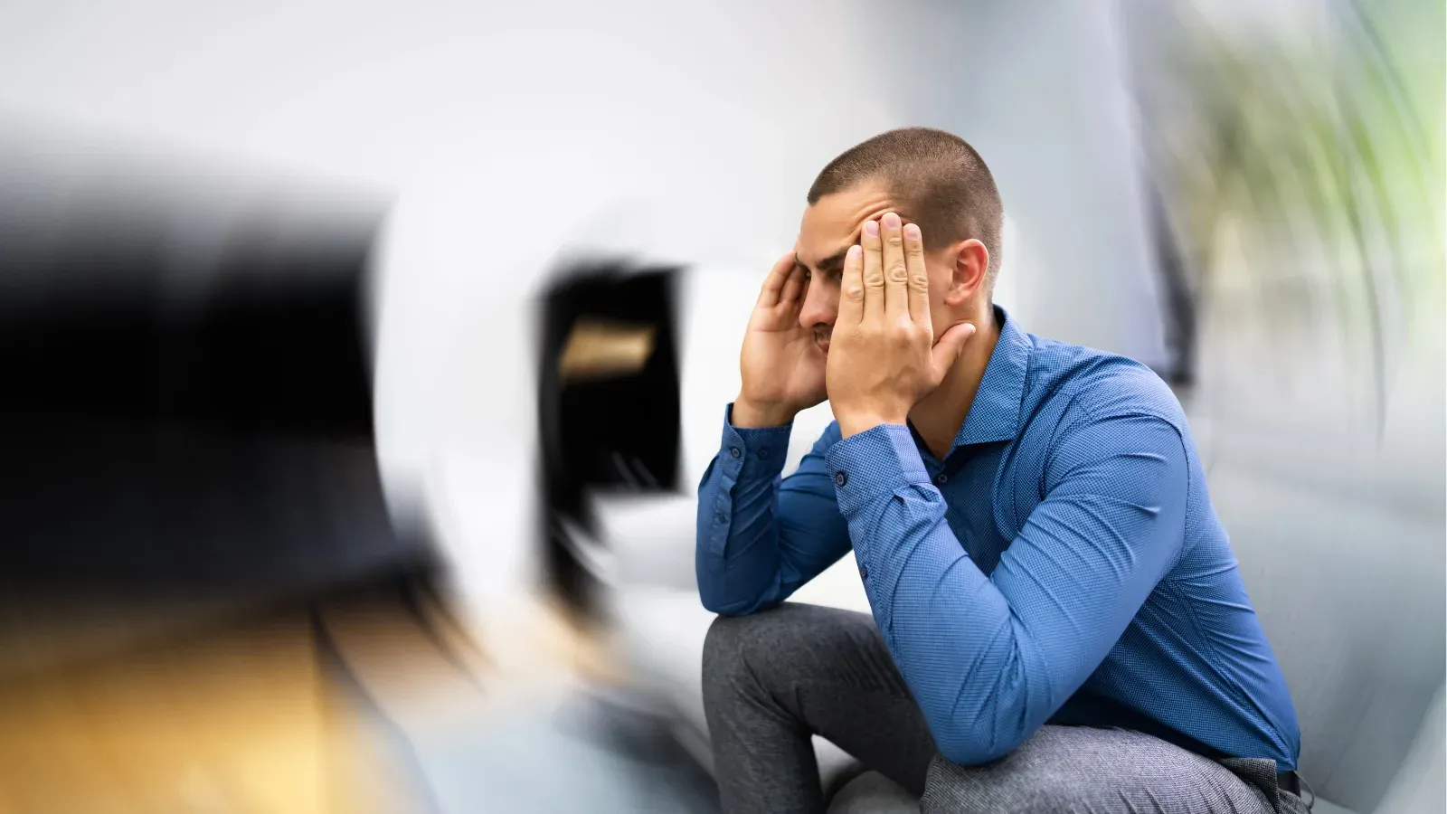 A man sitting with his head in his hands, the room blurred and tilting around him