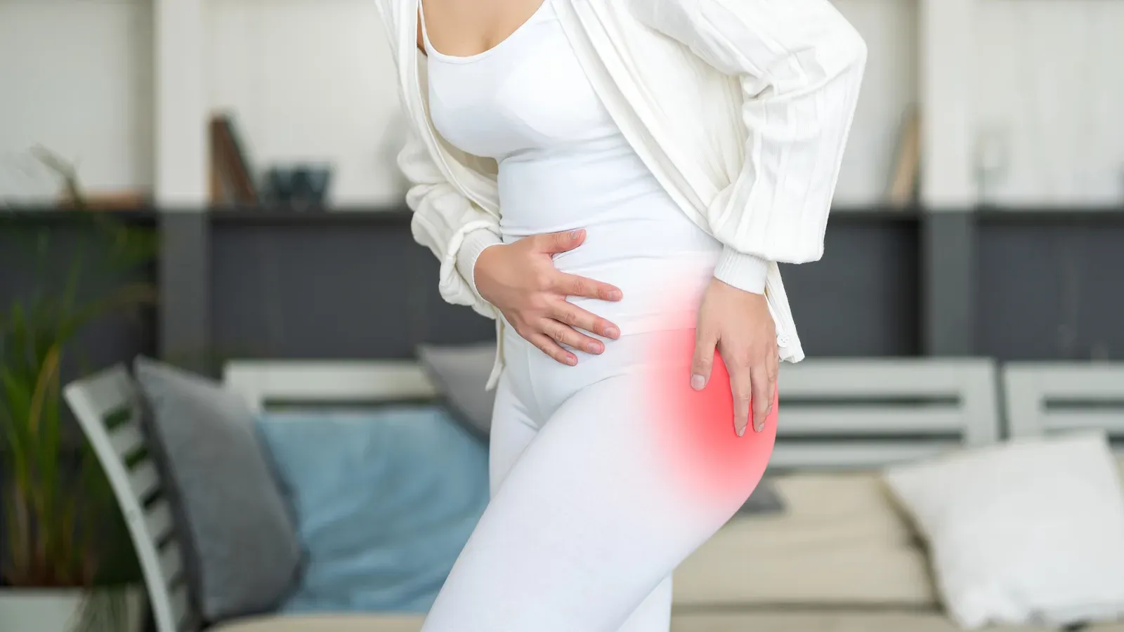 A woman standing with a hand on her hip, the hip joint highlighted in red