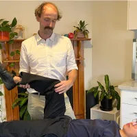 A physiotherapist lifting the straightened leg of a patient lying on a treatment table