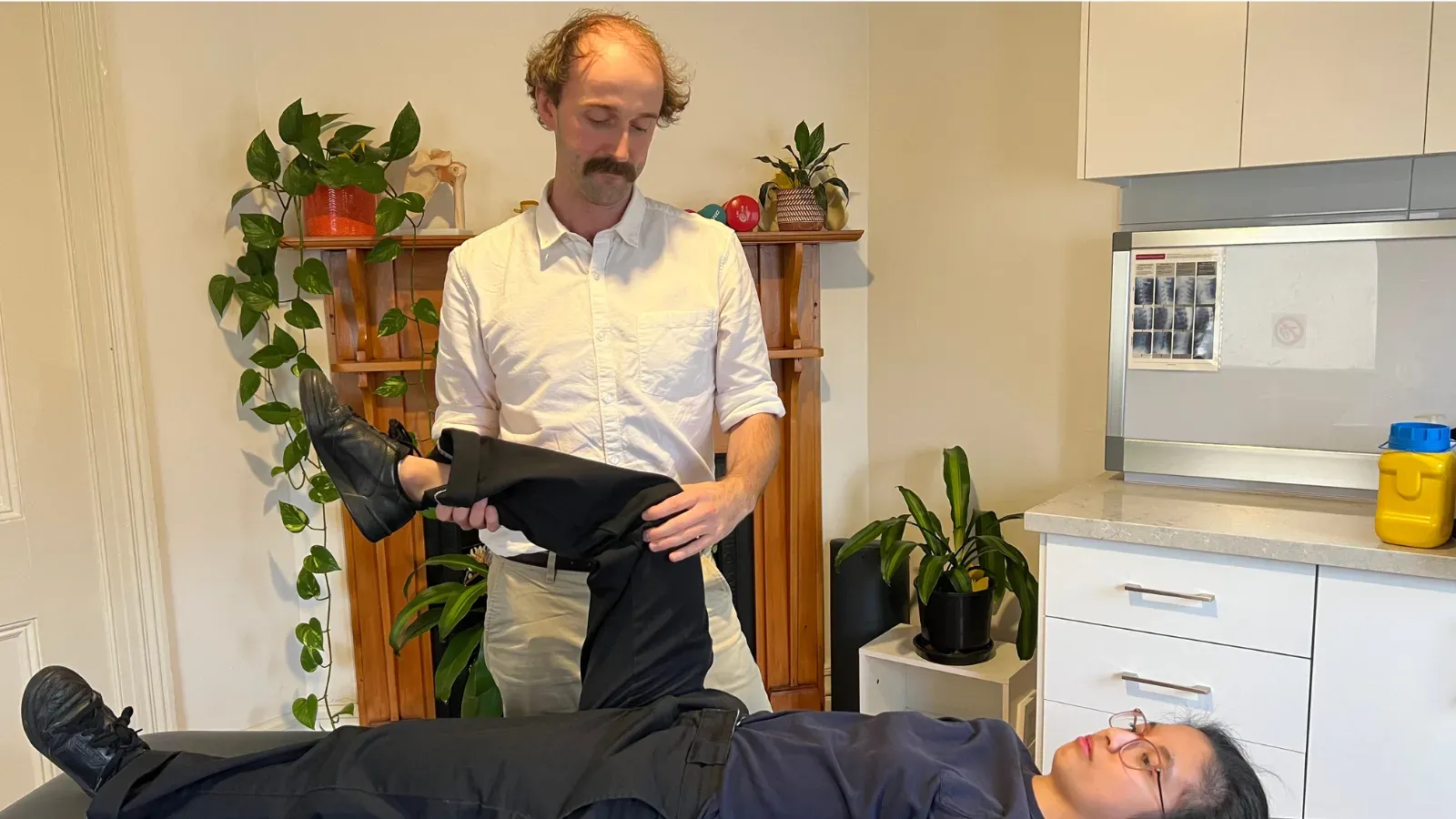 Andrew Macdonald lifting and rotating a patient's leg to test hip and knee movement