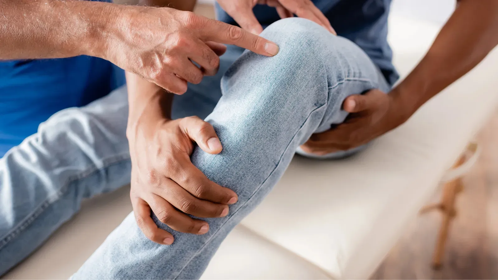 A physiotherapist pointing to a patient's knee while supporting it with both hands