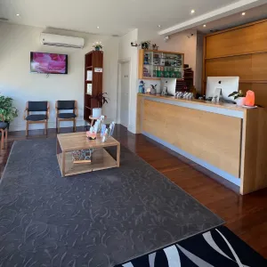 A clinic reception desk and waiting area with chairs along a street-facing window