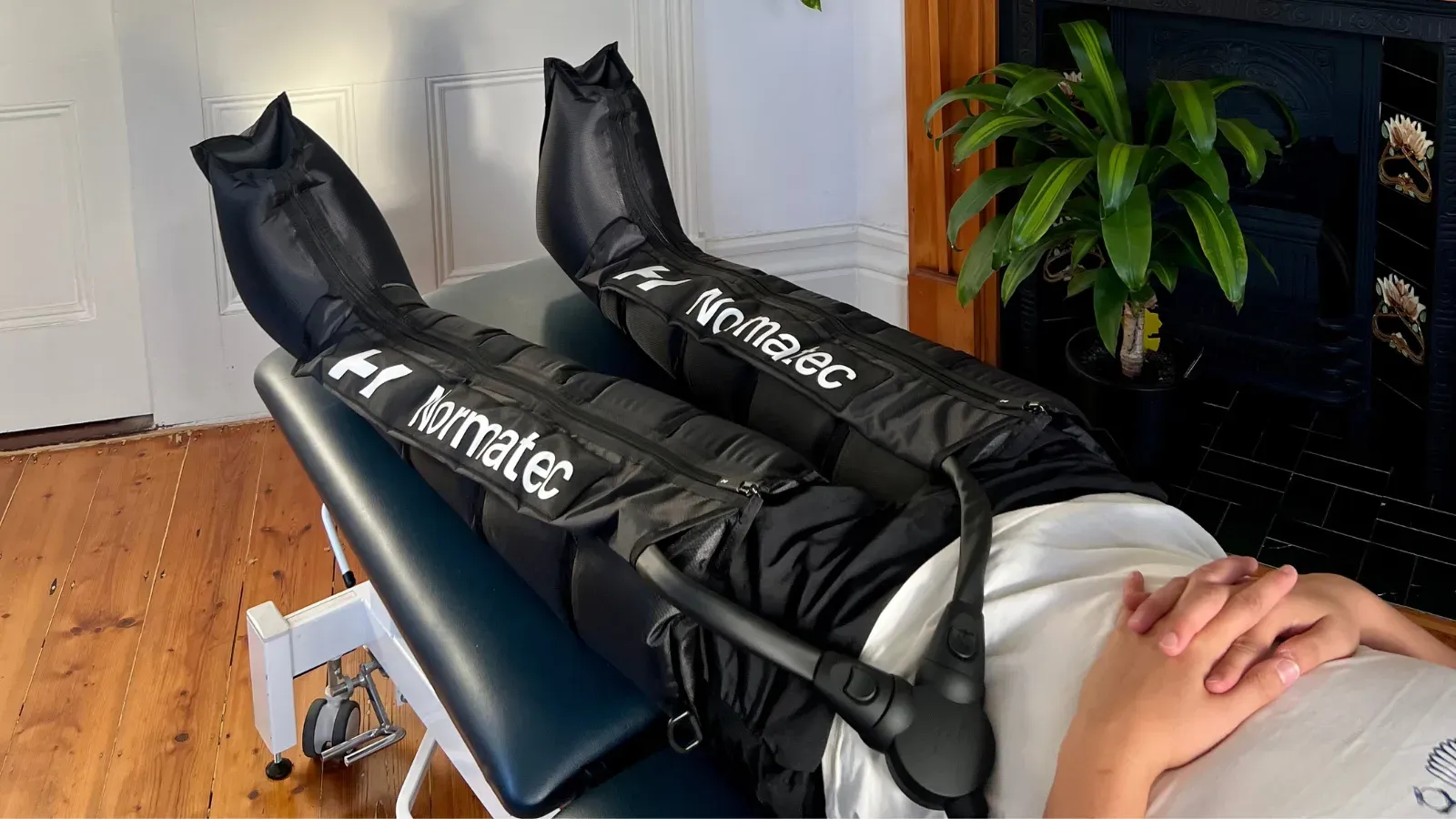 A pair of Normatec compression boots inflated around a person's legs on a treatment table